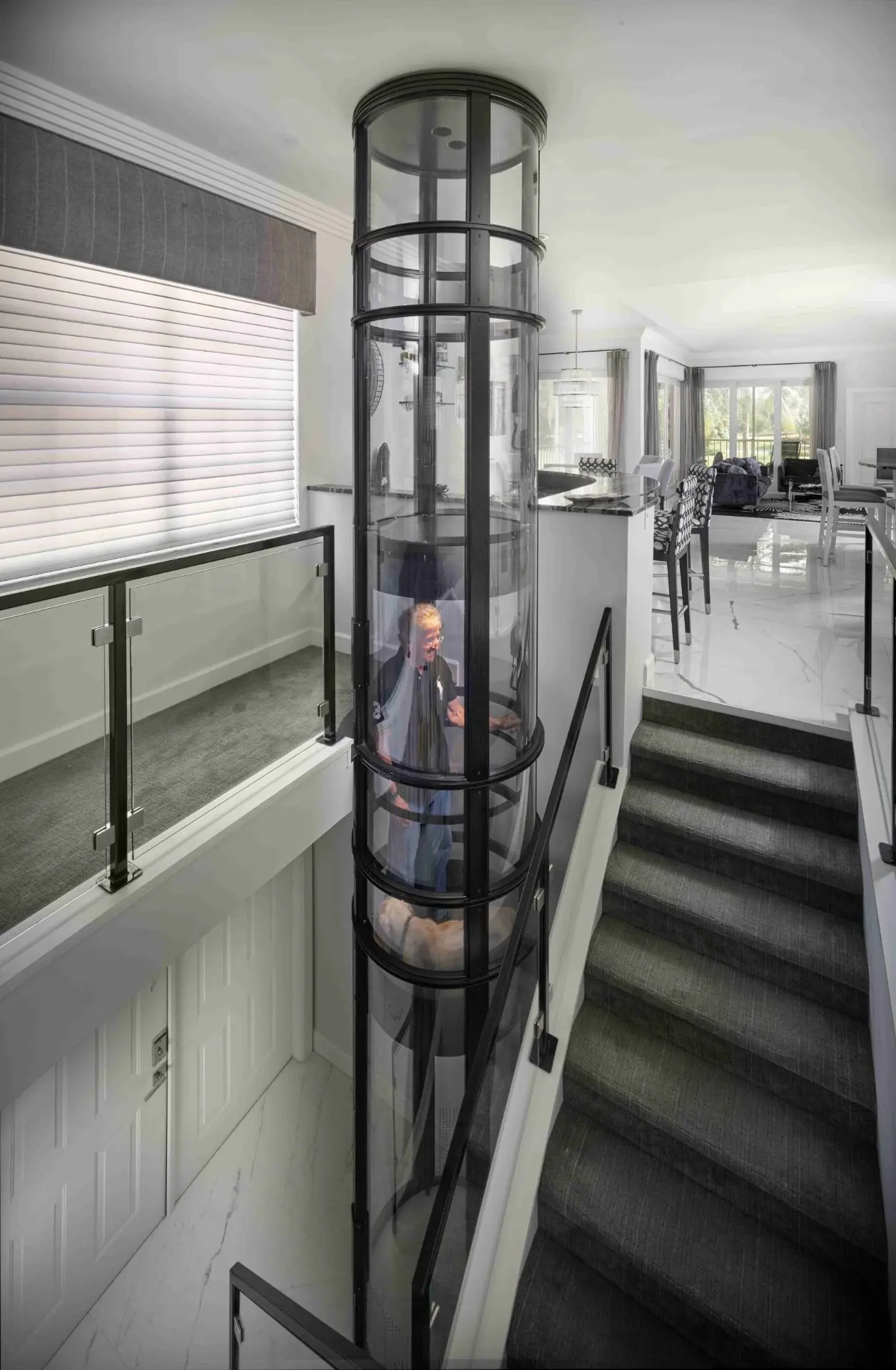 Modern home with transparent pneumatic vacuum elevator installed beside stairs for seamless movement.