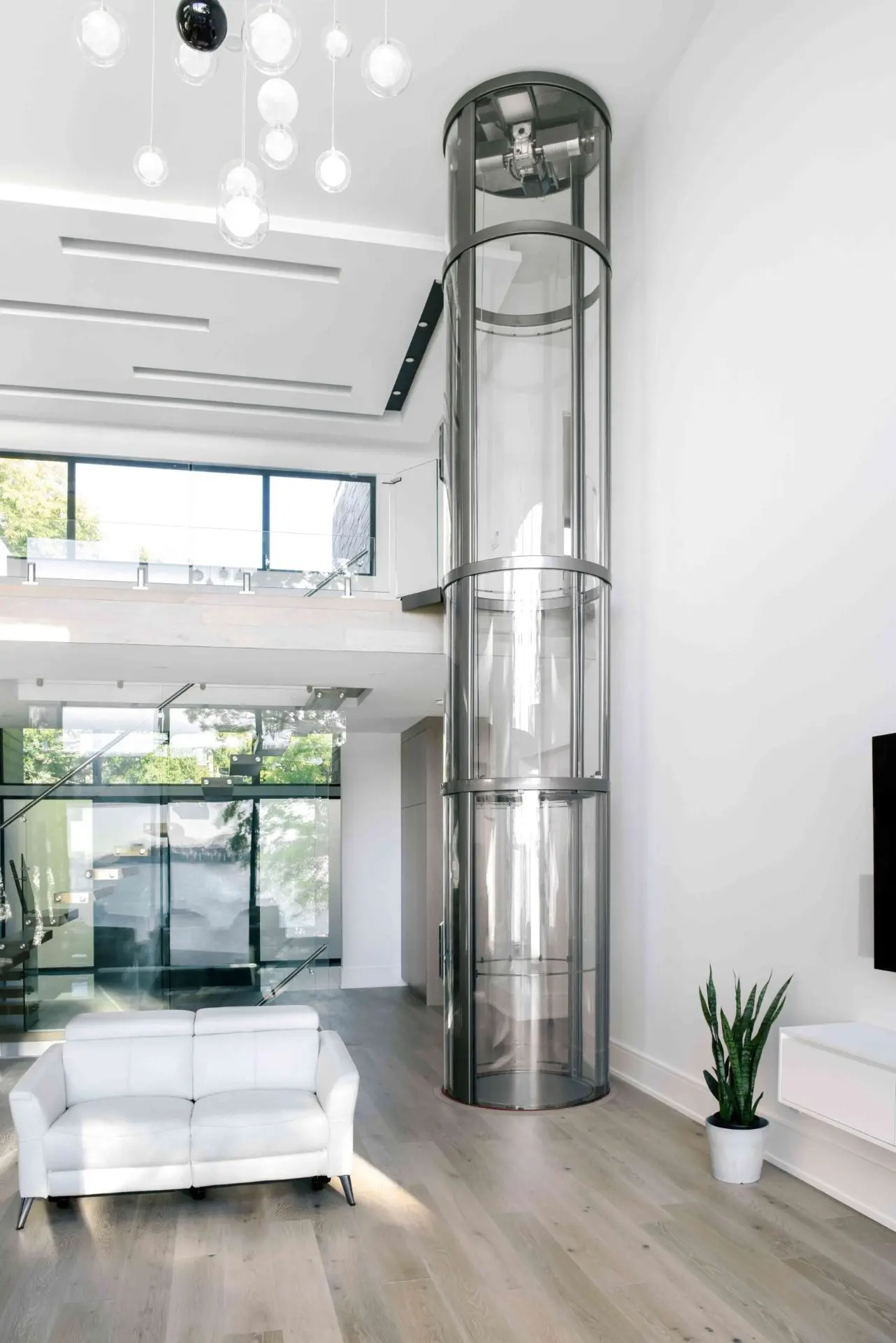Pneumatic vacuum elevator installation in a warehouse-style home with clear glass walls.