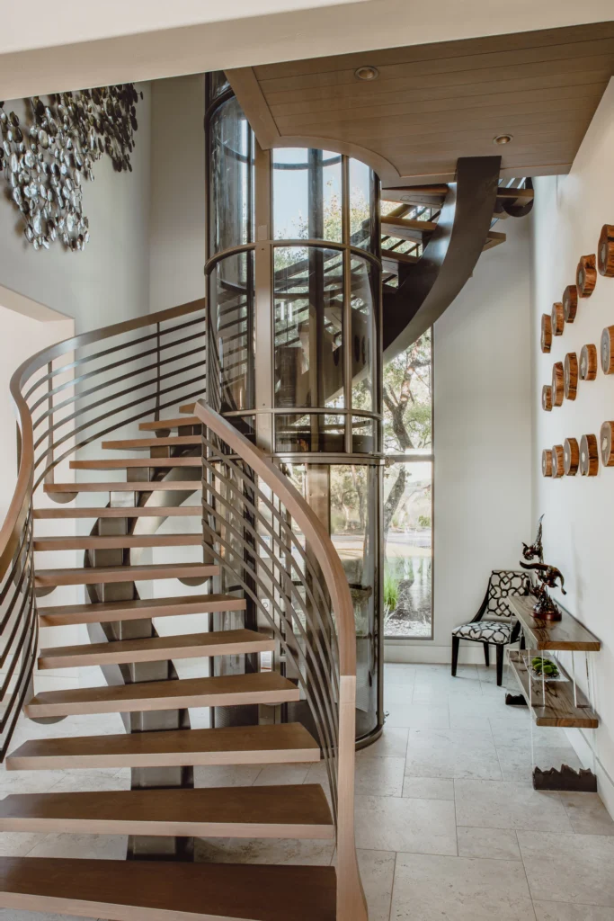 Round home elevator beside a floating spiral staircase in a Florida home