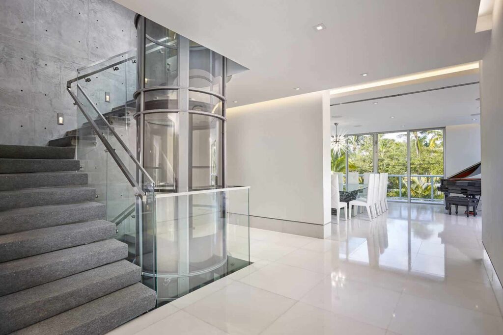 PVE30 pneumatic vacuum elevator beside a glass staircase in a luxury Florida home