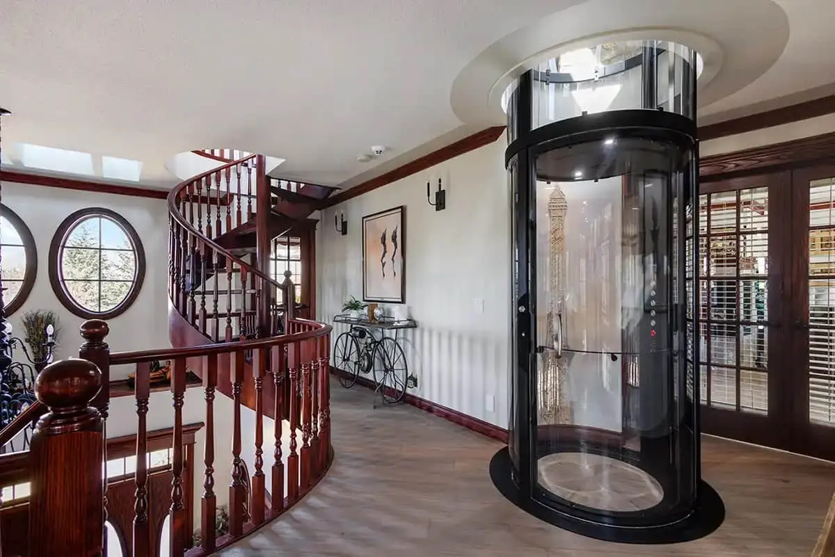 Black Savaria VueLift Mini residential elevator installed beside a curved staircase in a Florida home