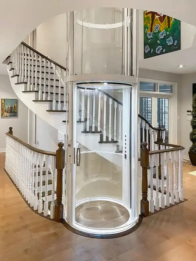 Savaria VueLift Mini round home elevator with transparent enclosure beside a staircase in Florida