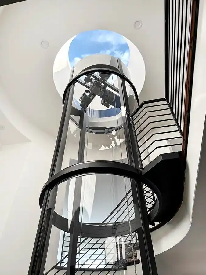 Savaria Vuelift round acrylic home elevator extending through multiple floors beneath a skylight in a modern Florida residence